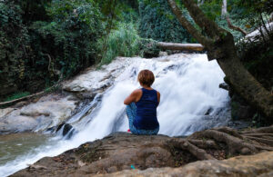 Deep in thought at a waterfall in Thailand while long term solo travelling.